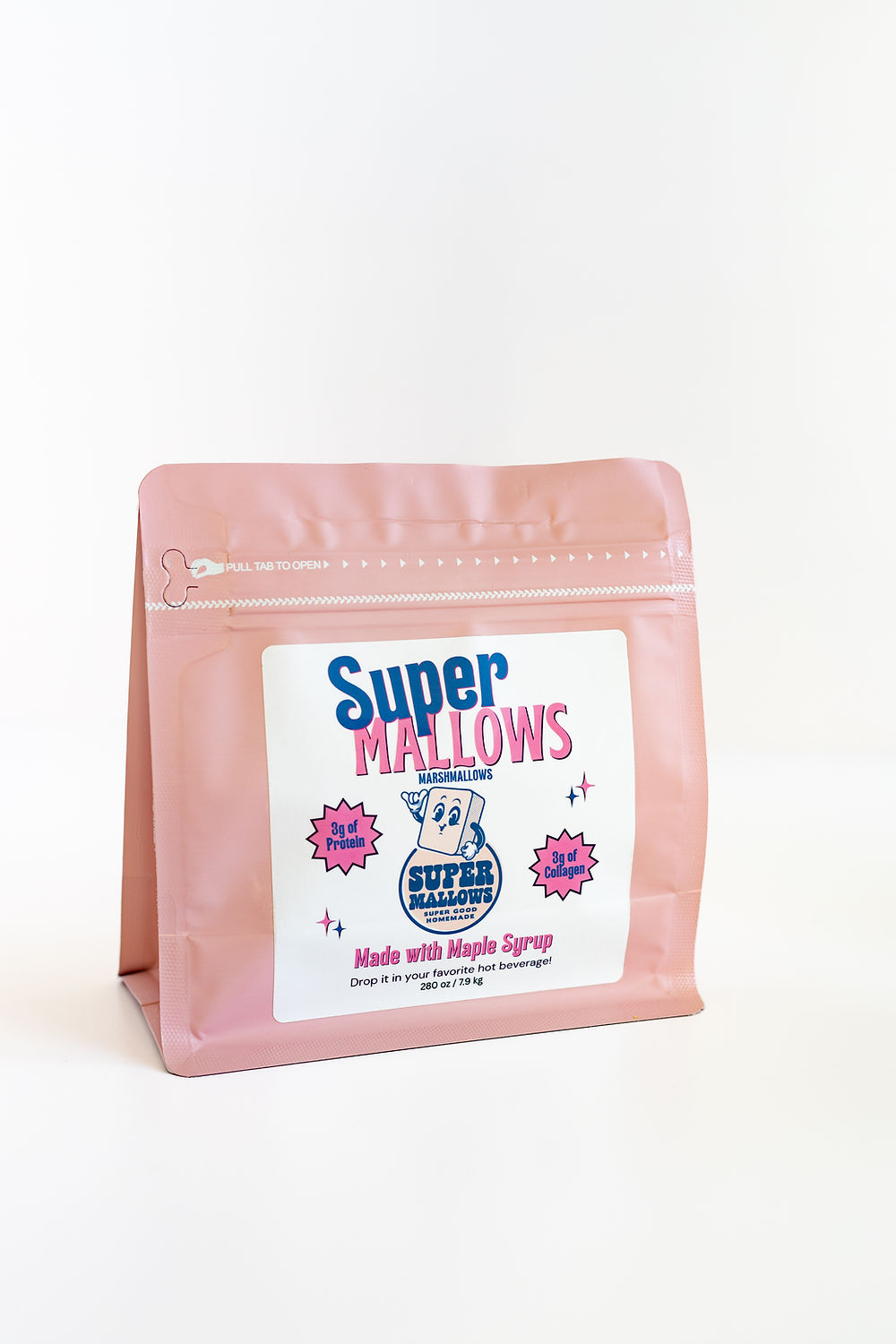 A pink resealable pouch of Super Mallows Original Super Mallow 8-pack sits on a white surface, featuring maple syrup-flavored artisanal marshmallows with playful cartoon stars, fun designs, and 0g fat per serving.