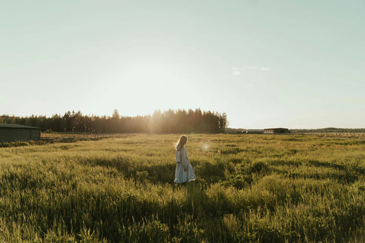 woman runs in an open field near sunset