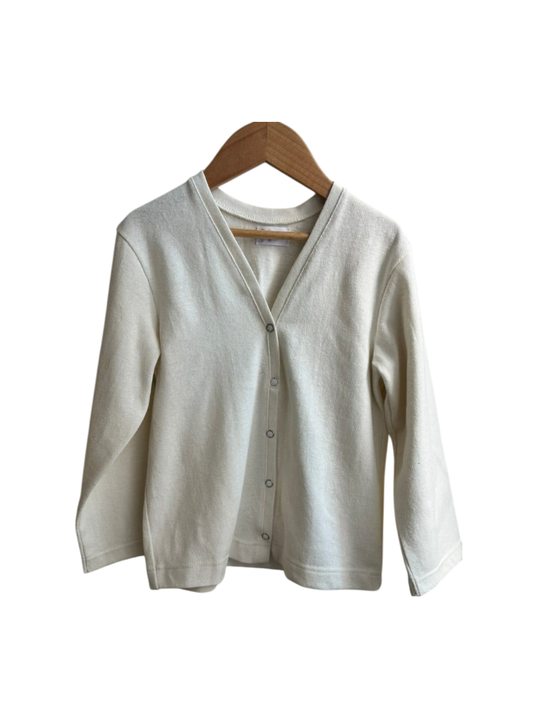 The TAKE CARE TOP hemp by cabane childrenswear is a cream long-sleeve cardigan, ethically handmade from hemp and organic cotton with a V-neckline and front buttons, shown on a wooden hanger against a white background.