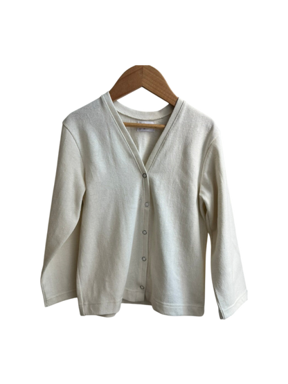 The TAKE CARE TOP hemp by cabane childrenswear is a cream long-sleeve cardigan, ethically handmade from hemp and organic cotton with a V-neckline and front buttons, shown on a wooden hanger against a white background.