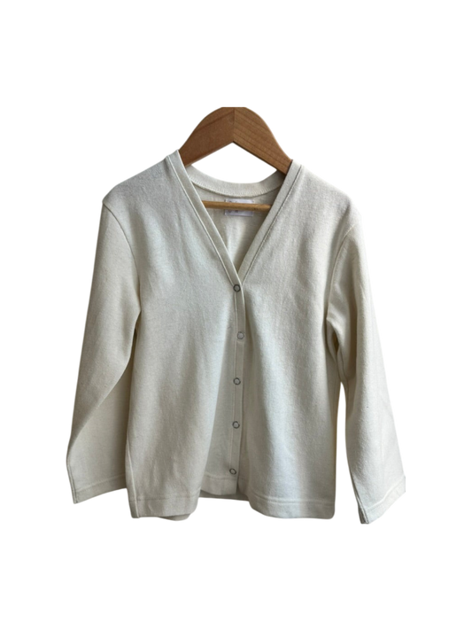 The TAKE CARE TOP hemp by cabane childrenswear is a cream long-sleeve cardigan, ethically handmade from hemp and organic cotton with a V-neckline and front buttons, shown on a wooden hanger against a white background.
