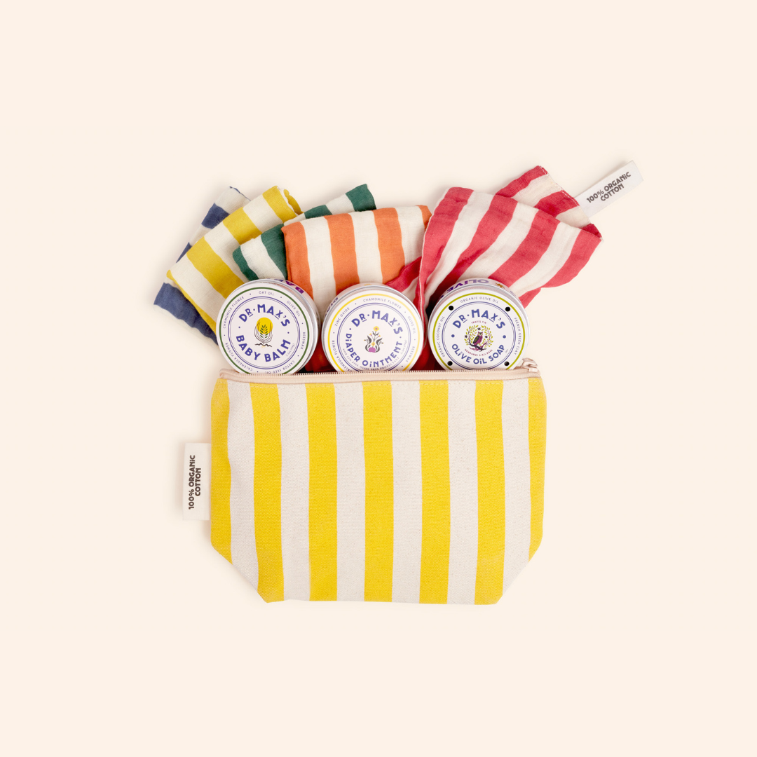 Dr. Max's Newborn Gift Box features a yellow-and-white striped pouch with three tins—olive oil soap and baby balm diaper ointment—plus four colorful rolled cloths in yellow, green, orange, and red, ideal for newborn essentials.