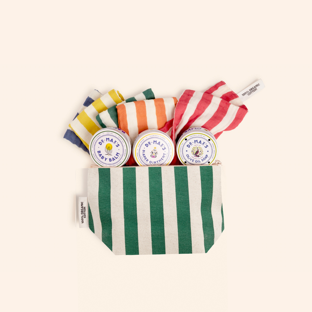 The Dr. Max's Newborn Gift Box features a green and white striped pouch with three round tins of Baby Balm diaper ointment and three striped cloths in yellow, orange, and red—perfect essentials for newborn care.