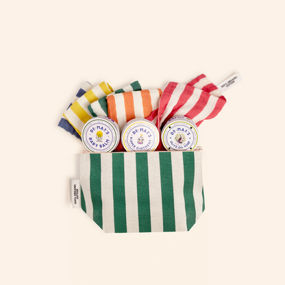 The Dr. Max's Newborn Gift Box features a green and white striped pouch with three round tins of Baby Balm diaper ointment and three striped cloths in yellow, orange, and red—perfect essentials for newborn care.