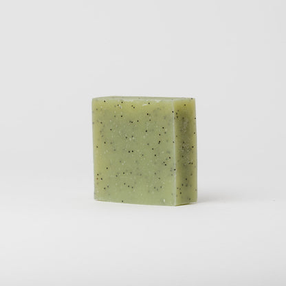 A square bar of My Neighbor’s Tallow Blue Tansy & Raw Honey Tallow Soap with small black specks stands upright on a plain white background.