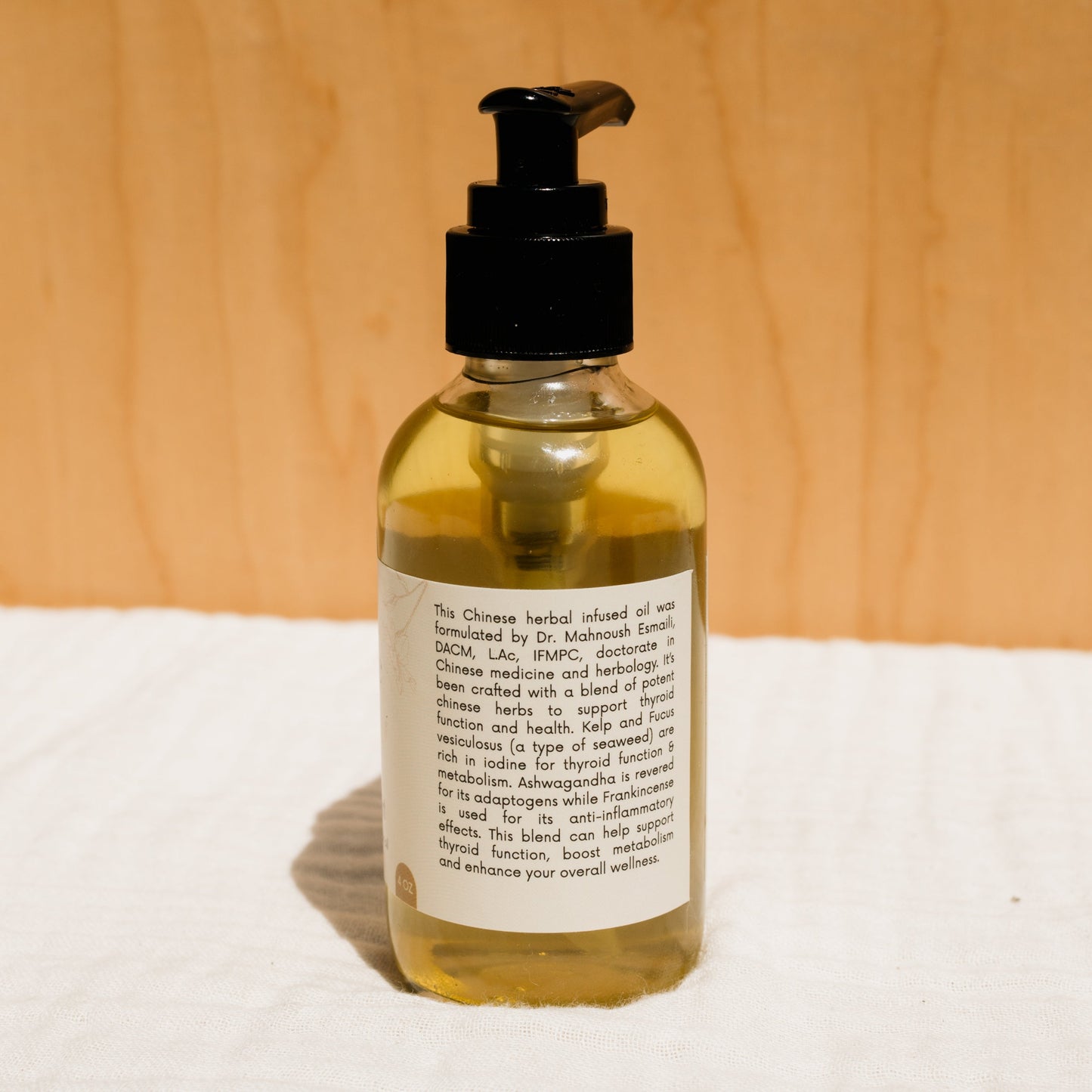 A bottle of Honeybee Hippie's herbal infused castor oil packs with a black pump dispenser stands against a light background, featuring a partially visible label hinting at holistic health benefits.