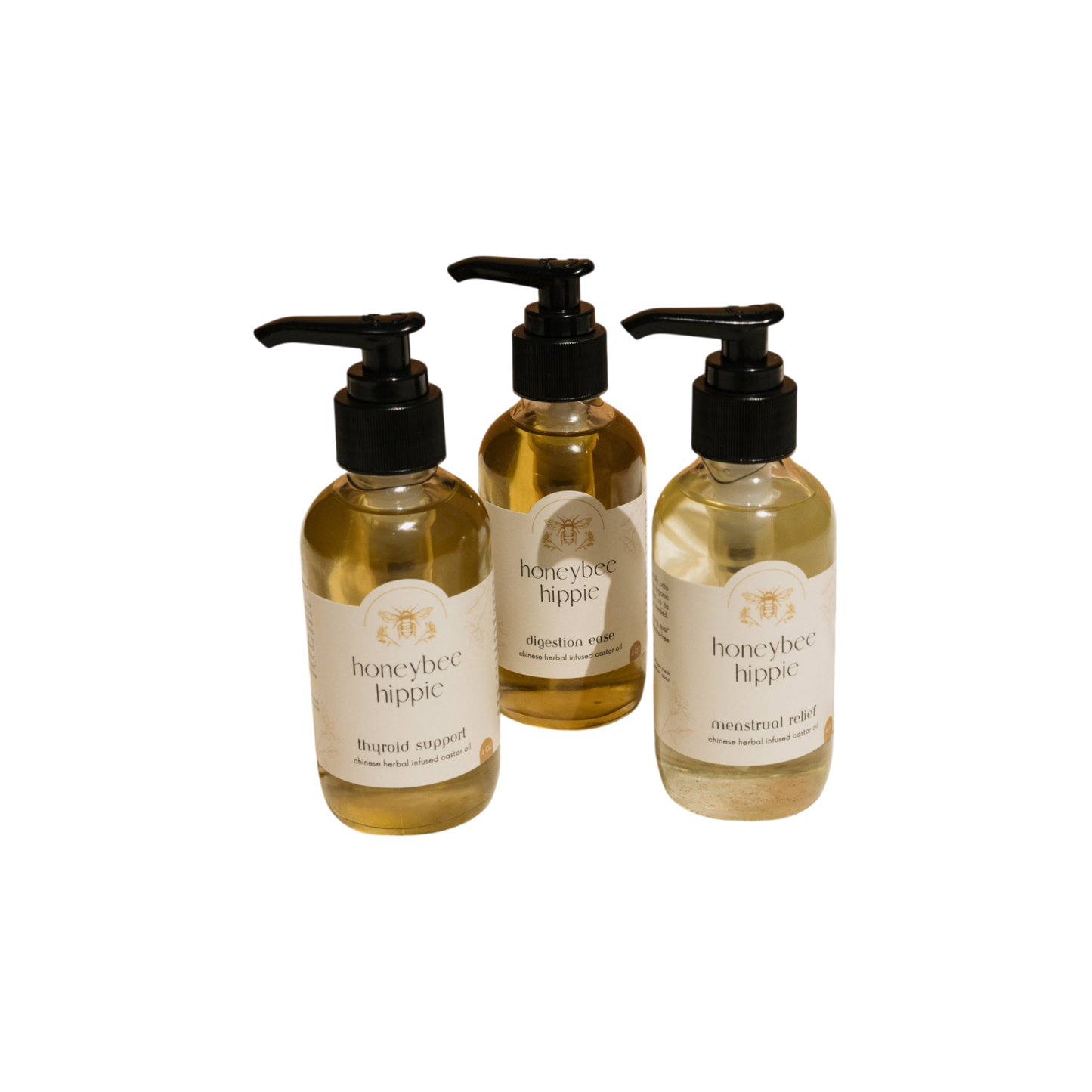 Three bottles of Honeybee Hippie herbal-infused castor oil packs, featuring labels that say "thyroid support," "digestion support," and "menstrual relief," are arranged in a triangle against a black background, highlighting their holistic health benefits.