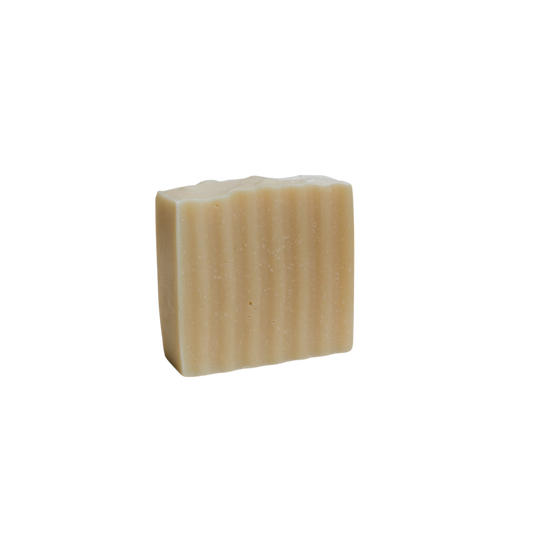 The Honeybee Hippie honeybee tallow soap bar, with its rectangular shape and light beige tone, features a wavy, ribbed texture. It stands upright against a white background and is infused with the soothing essence of organic herbs.