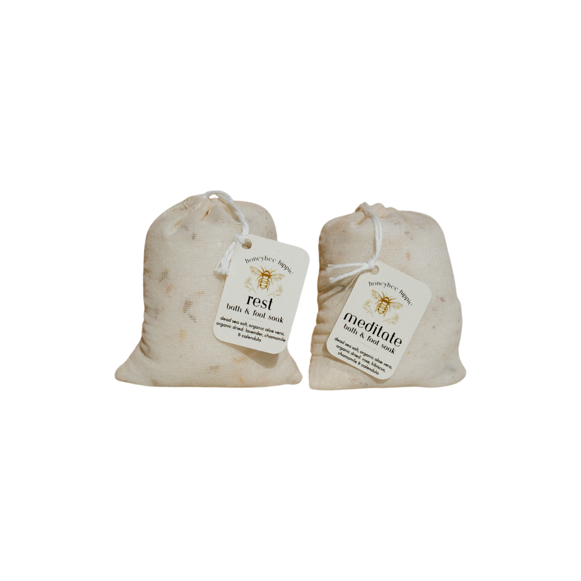 Two small beige fabric pouches from Honeybee Hippie, including the "meditate bath soak," feature mineral-rich blends and organic botanicals, each with a string tie and label, displayed on a plain black background.