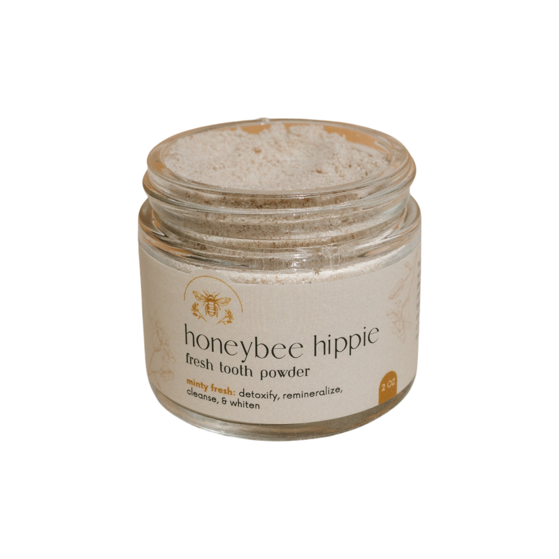Honeybee Hippie's fresh tooth powder detoxifies, whitens, and remineralizes teeth while delivering minty freshness. A partially filled jar holds this revitalizing formulation designed to cleanse your smile.