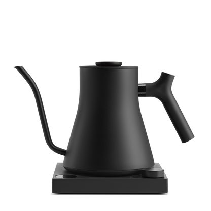 A sleek, modern black Stagg EKG Pro Electric Kettle by Fellow Wholesale, featuring a long, curved spout and an ergonomic handle, sits on its base. This minimalist and functional kettle is perfect for precise pouring, with customizable brew settings ideal for making pour-over coffee or tea.