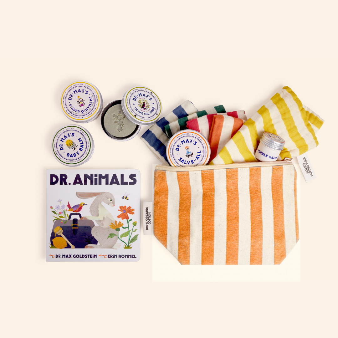 A flat lay displays Dr. Max's New Parent Gift Box with skincare tins, a striped orange pouch, colorful cloths, diaper ointment, a balm stick, and "Dr. Animals," an illustrated children's book.
