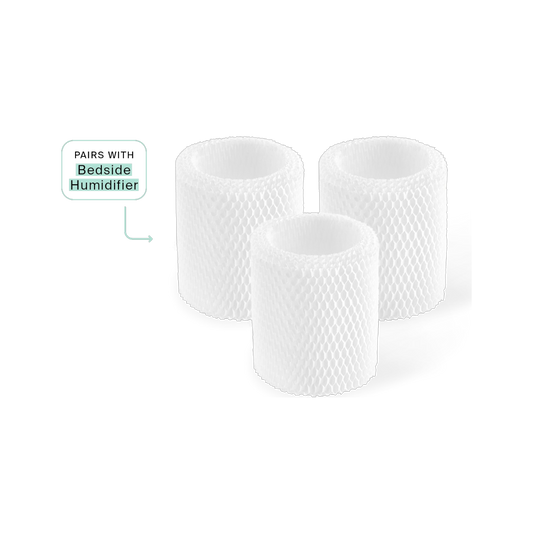 A black background features three white cylindrical mesh filters labeled with an arrow as "Bedside Humidifier," highlighting their anti-microbial properties for a healthier environment. They are the Canopy Bedside Humidifier Filter 3-Pack.
