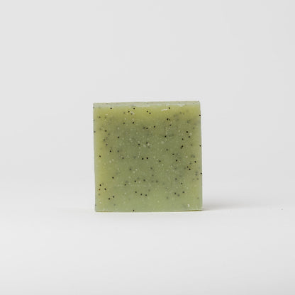 A square, green bar of My Neighbor’s Tallow Blue Tansy & Raw Honey Tallow Soap with small black speckles is centered against a plain white background.