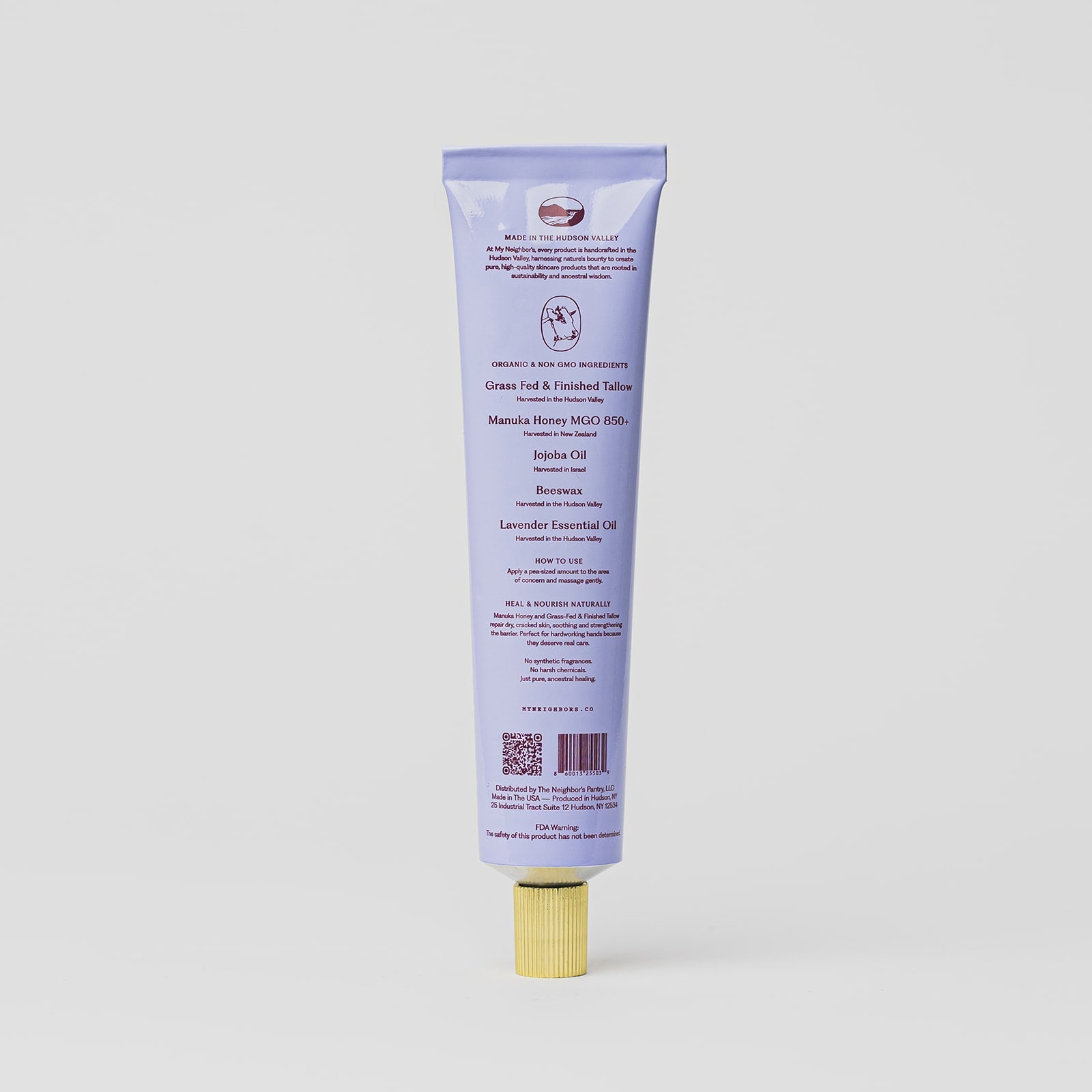 A lavender-colored tube of My Neighbor’s Tallow Manuka Honey & Lavender hand balm stands upright against a white background, displaying product details and ingredients in purple text with a QR code near the base.