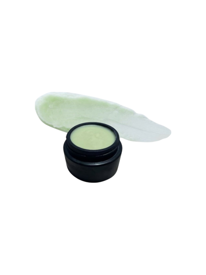 A small black jar of Ancestral Blue 2.4oz by Wild Mamas, filled with light green cream made from grass-fed tallow, sits in front of a smear of the same cream on a white background.