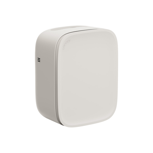 The Canopy Bedside Air Purifier is a sleek, modern white unit with rounded edges and a minimalist design. It features a small side vent and operates ultra-quietly, making it perfect for bedrooms.