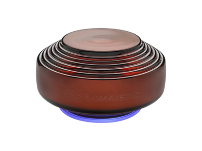 Amber by Somavedic USA is a round, dark amber device with ribbed rings on top and a glowing blue base, bearing “SOMAVEDIC” on its side. It’s designed for EMF mitigation and protection against 5G effects.