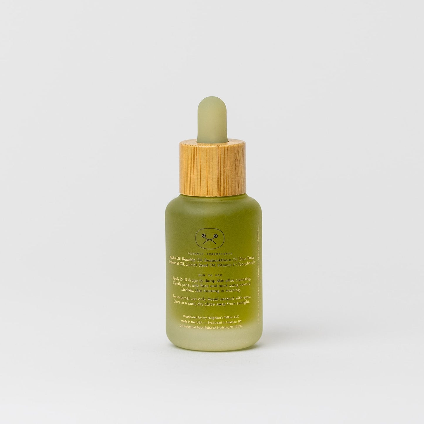 A green frosted glass dropper bottle of My Neighbor’s Tallow Blue Moon Face Serum with a wooden cap and gold text stands upright against a white background—ideal for sensitive skin.