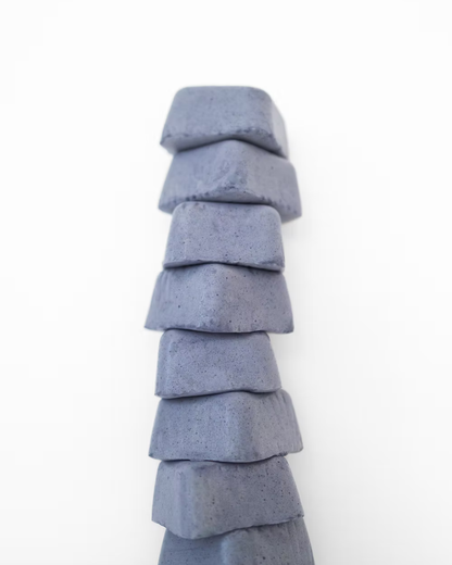 A stack of eight blue-gray blocks stands tall against a white background, evoking the calm strength found in Super Mallows' Beauty Mallow Super Mallow 8-pack—a glow-boosting treat with pearl powder for radiant skin.