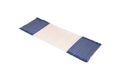 An organic cotton yoga mat by Bennd Yoga, named the Indigo Ayurvedic Yoga Mat, incorporates a beige center with blue-striped fringed edges.