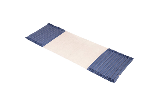 An organic cotton yoga mat by Bennd Yoga, named the Indigo Ayurvedic Yoga Mat, incorporates a beige center with blue-striped fringed edges.