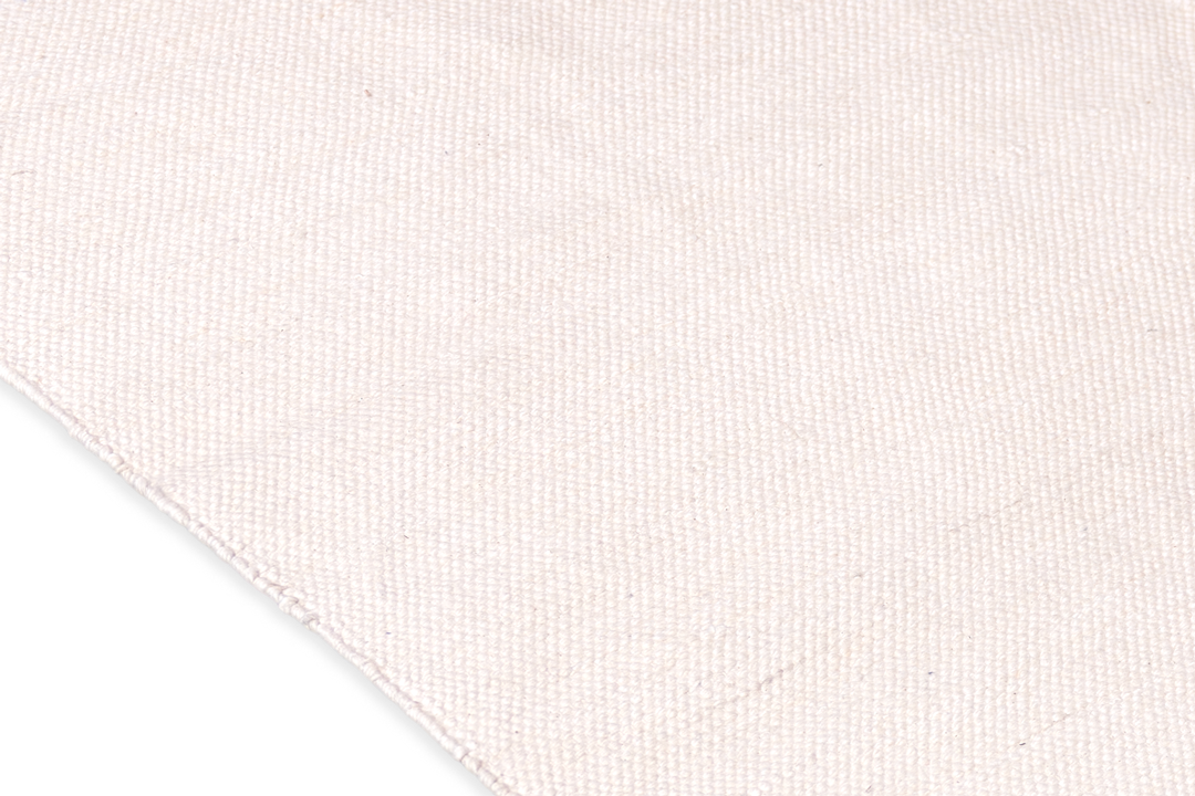 A close-up shows the textured beige fabric crafted from organic cotton on the right, set against a contrasting black background on the left, echoing the timeless design of Bennd Yoga's Indigo Ayurvedic Yoga Mat.