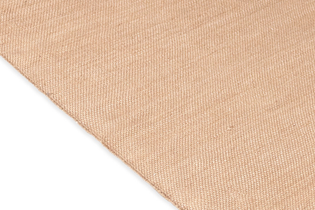 Close-up of the Harda Ayurvedic Yoga Mat's textured beige fabric, reminiscent of organic cotton and oriented diagonally. The weave is visible, displaying a simple and even pattern. The bottom left corner features a solid black background, providing contrast to the natural beauty of Bennd Yoga's textile.