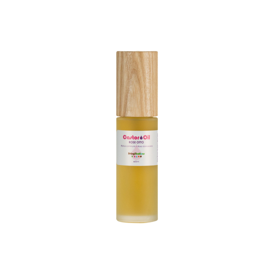 The product is a glass bottle with a wooden cap containing Living Libations' Castor Oil + Rose Otto. It features a white label with red text emphasizing its rich ricinoleic acids for nourishing benefits.