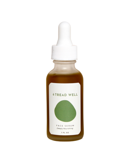 A brown glass dropper bottle labeled "& Tread Well Face Serum" with a green oval design and white cap. This 1 fl oz natural serum is deeply nourishing and hydrating.