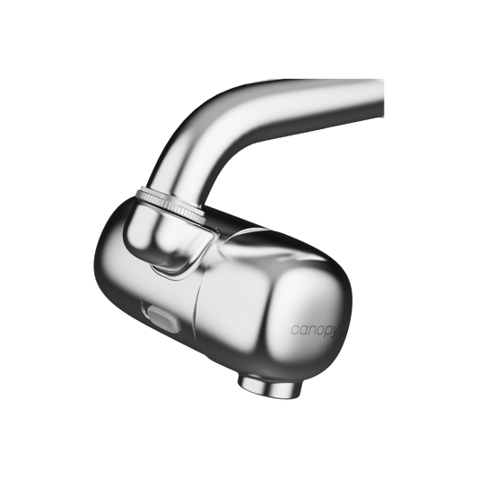 A close-up of the Canopy Faucet Filter shows its modern, rounded chrome design with a side button, attached to a faucet. The Canopy filter delivers cleaner water for a healthy lifestyle.