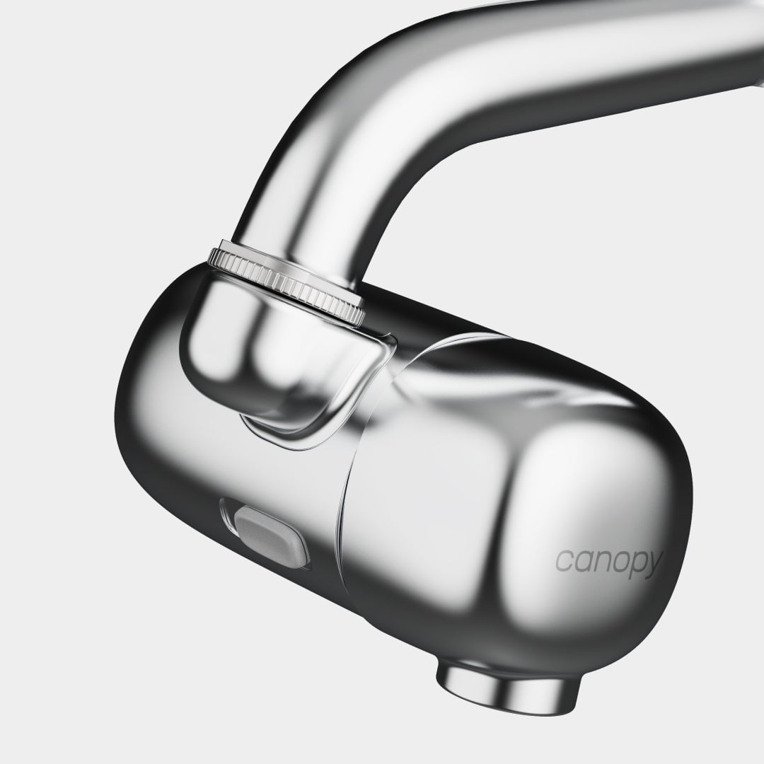 Close-up of a sleek, modern Canopy Faucet Filter in silver attached to a faucet. The filter features the Canopy brand name, against a plain white background. Fulfilled by Canopy for quality and convenience.