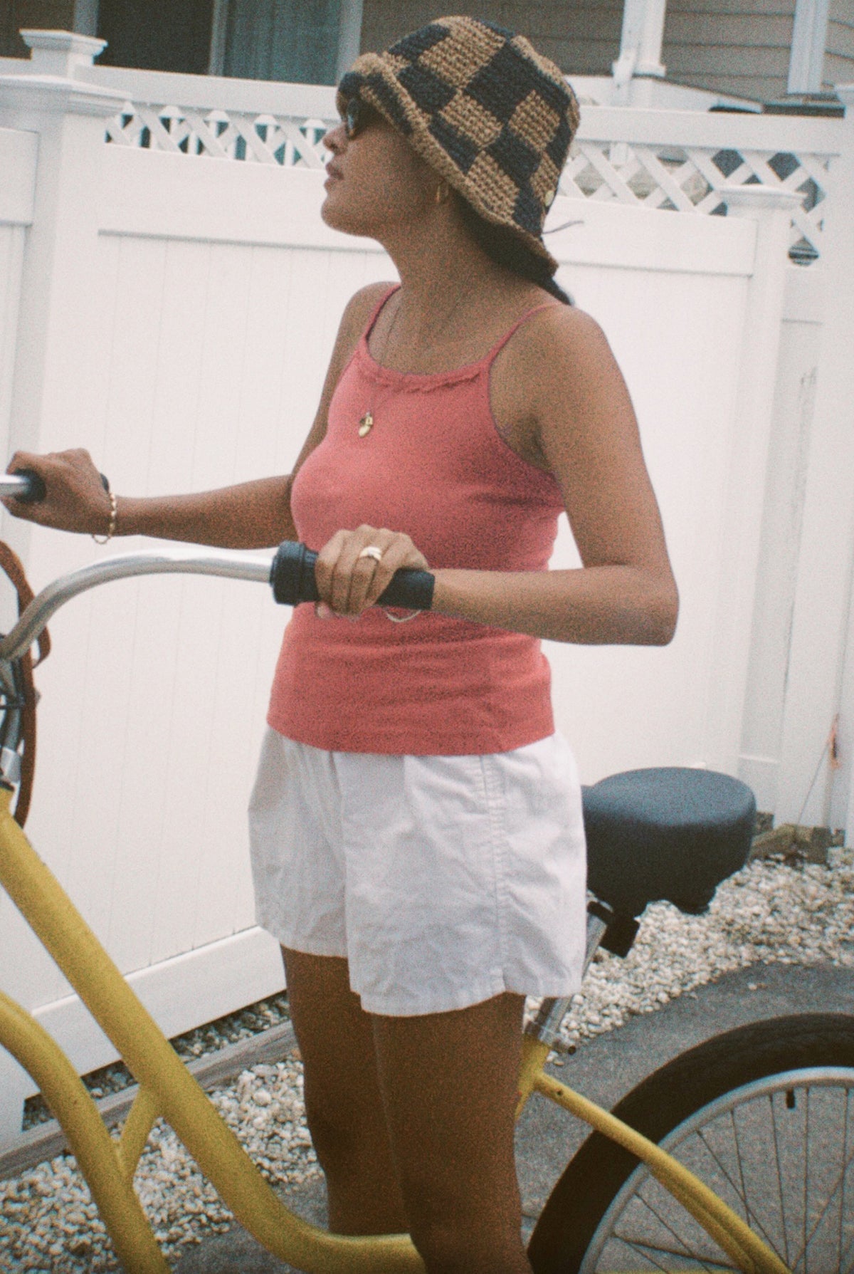 Rose - 
Wearing LA RELAXED's Frill Camisole in pink, a person with a checkered bucket hat, sunglasses, and white shorts stands outdoors holding a yellow bike, with a white fence and house behind them.