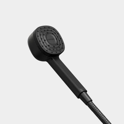 The Canopy Handheld Filtered Showerhead features a sleek black design with a square, rounded-edge nozzle and small, evenly spaced water holes. A flexible hose completes the set, all shown against a plain gray background.