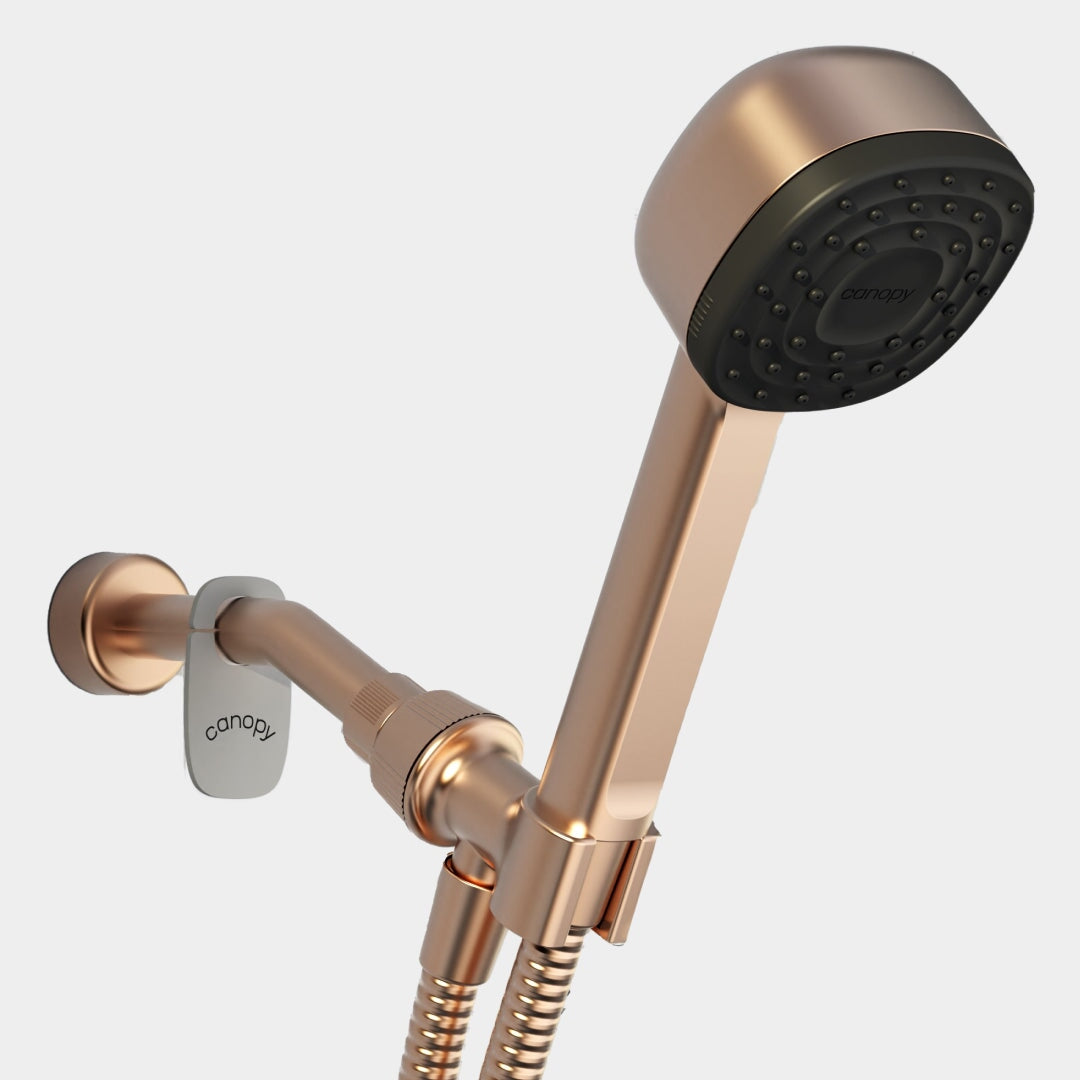The Canopy Handheld Filtered Showerhead features a rose gold finish, black spray face, flexible hose, and wall mount. Each piece is labeled and fulfilled by Canopy for a sleek, modern touch.