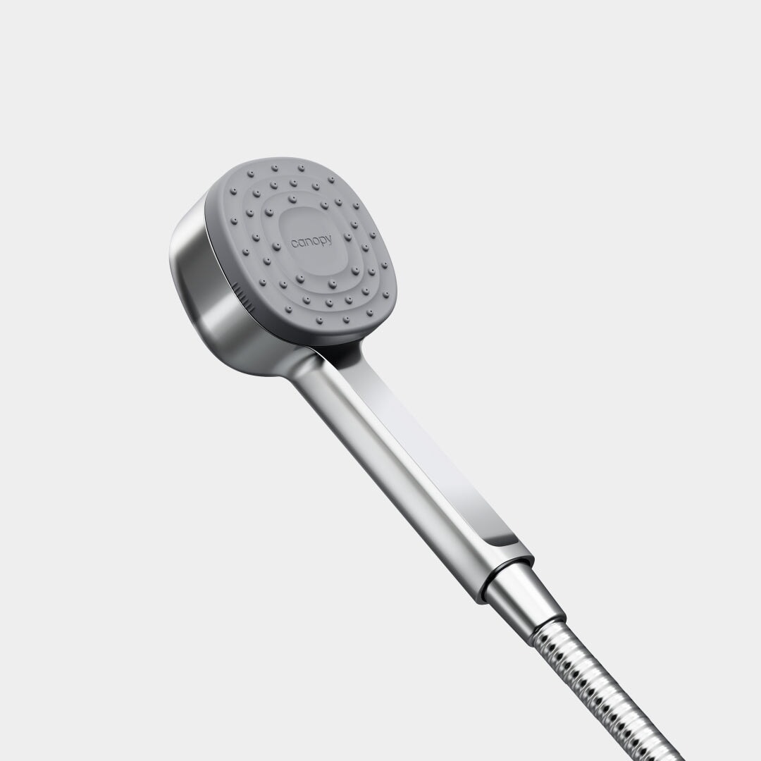 The Canopy Handheld Filtered Showerhead, featuring a modern silver square design with rounded edges and a flexible metal hose, is shown against a plain light gray background. The Canopy brand name appears on the shower face.