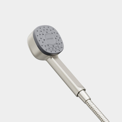 The Canopy Handheld Filtered Showerhead features a square gray spray face, sleek silver handle, and flexible metal hose, showcased against a minimalist white background.