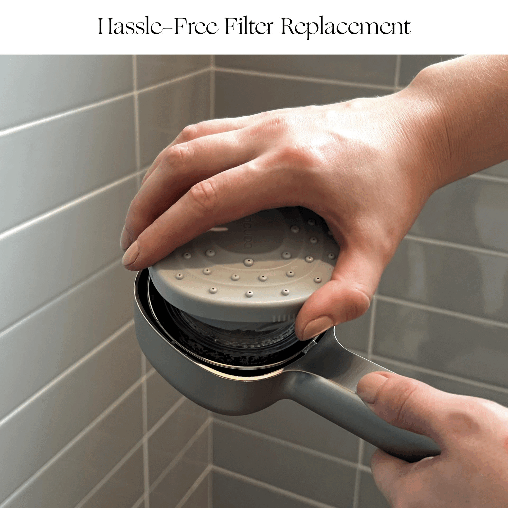 Close-up of hands unscrewing and removing a Canopy Handheld Filtered Showerhead filter, showing easy, hassle-free filter replacement. Light gray tile background. Top text: "Hassle-Free Filter Replacement.