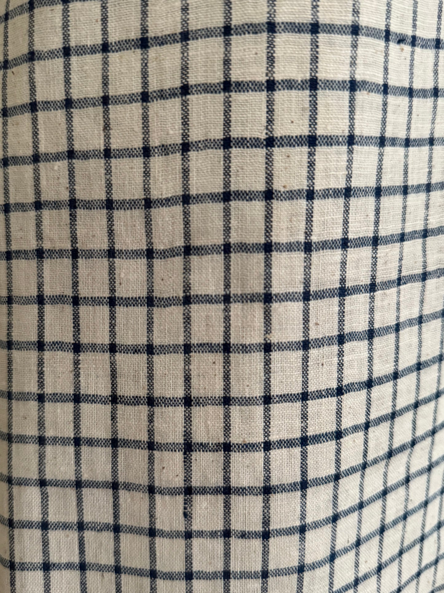 Close-up of the PER SE PANT blue check by cabane childrenswear, featuring ethically handmade beige organic cotton khadi with navy blue check grid lines in a classic plaid design and subtly visible texture.