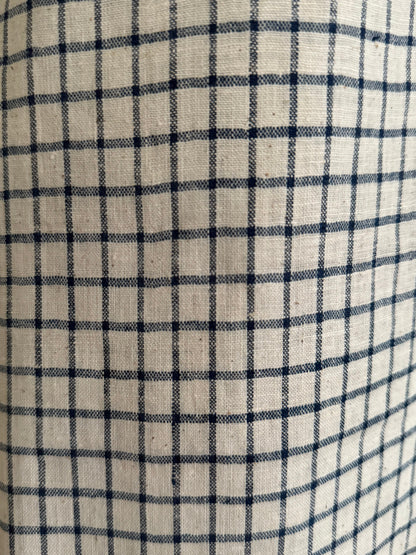 Close-up of the PER SE PANT blue check by cabane childrenswear, featuring ethically handmade beige organic cotton khadi with navy blue check grid lines in a classic plaid design and subtly visible texture.