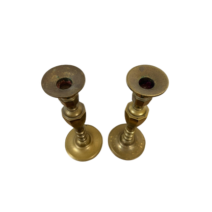 A stunning pair of Vintage Brass Candle Holders from Shoppe Maison, featuring a simple, cylindrical design and a polished finish. The flat top part, slightly wider than the stem and designed for candle insertion, highlights their elegant craftsmanship. Displayed against a black background, they exemplify the exquisite homewares collection offered by Shoppe Maison.