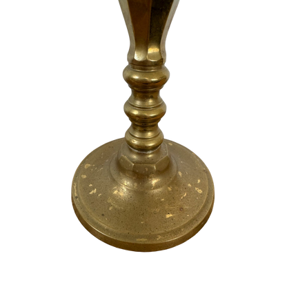 A close-up view of the base of the Vintage Brass Candle Holders by Shoppe Maison. The round base features a slightly textured surface, and the stem displays decorative ridges. The brass's tarnished, aged appearance adds to its charm against the completely black background—perfect choice for homewares.