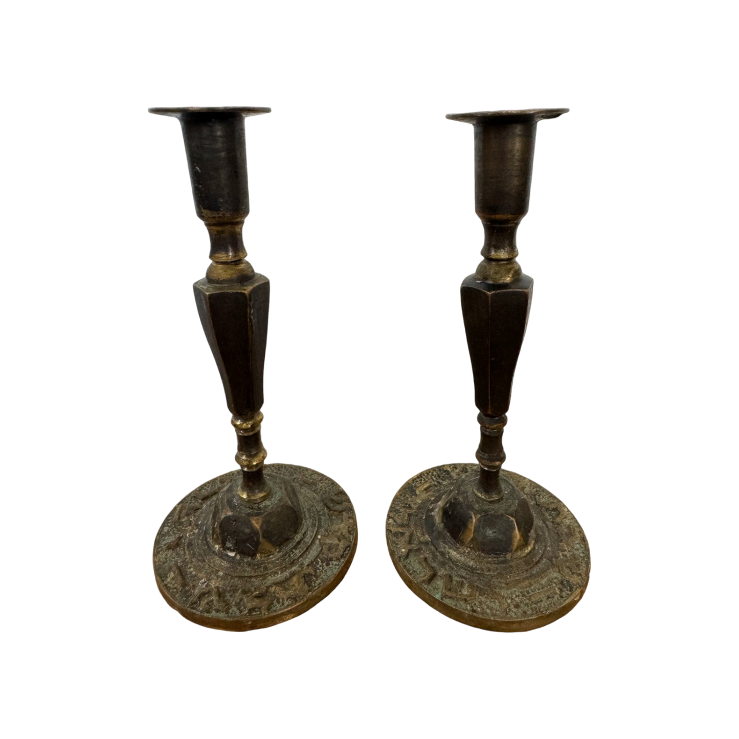 A pair of Shoppe Maison Vintage Shabbat Candle Holders with tall, tapered shafts and wide, circular bases featuring intricate etched designs, set against a black background. These brass candlesticks show signs of tarnish, adding to their antique appearance.