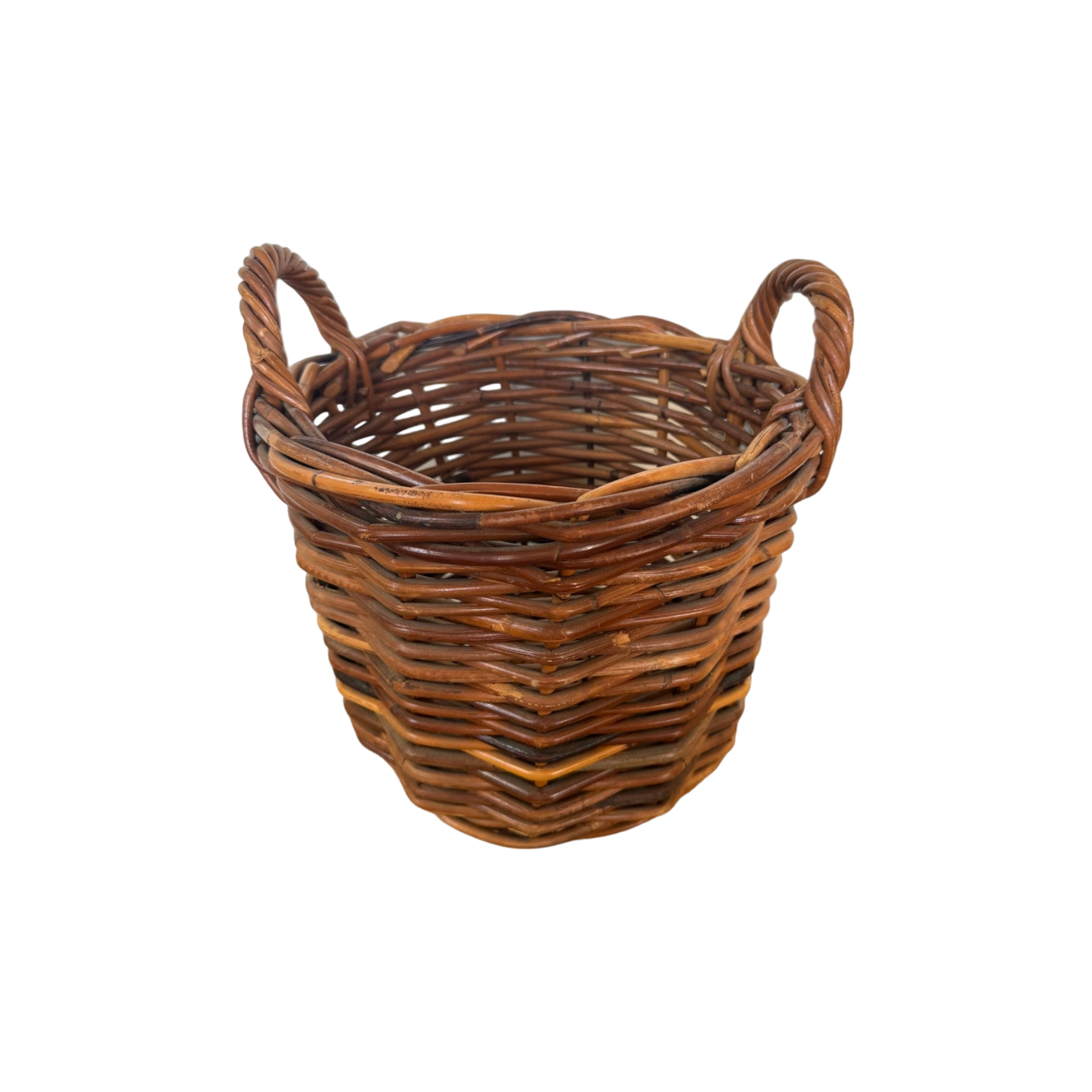 The Vintage Woven Basket with Handles from Shoppe Maison is a round, slightly tapered basket made of natural brown rattan. It features two looped handles on either side and boasts a tight, uniform weave.