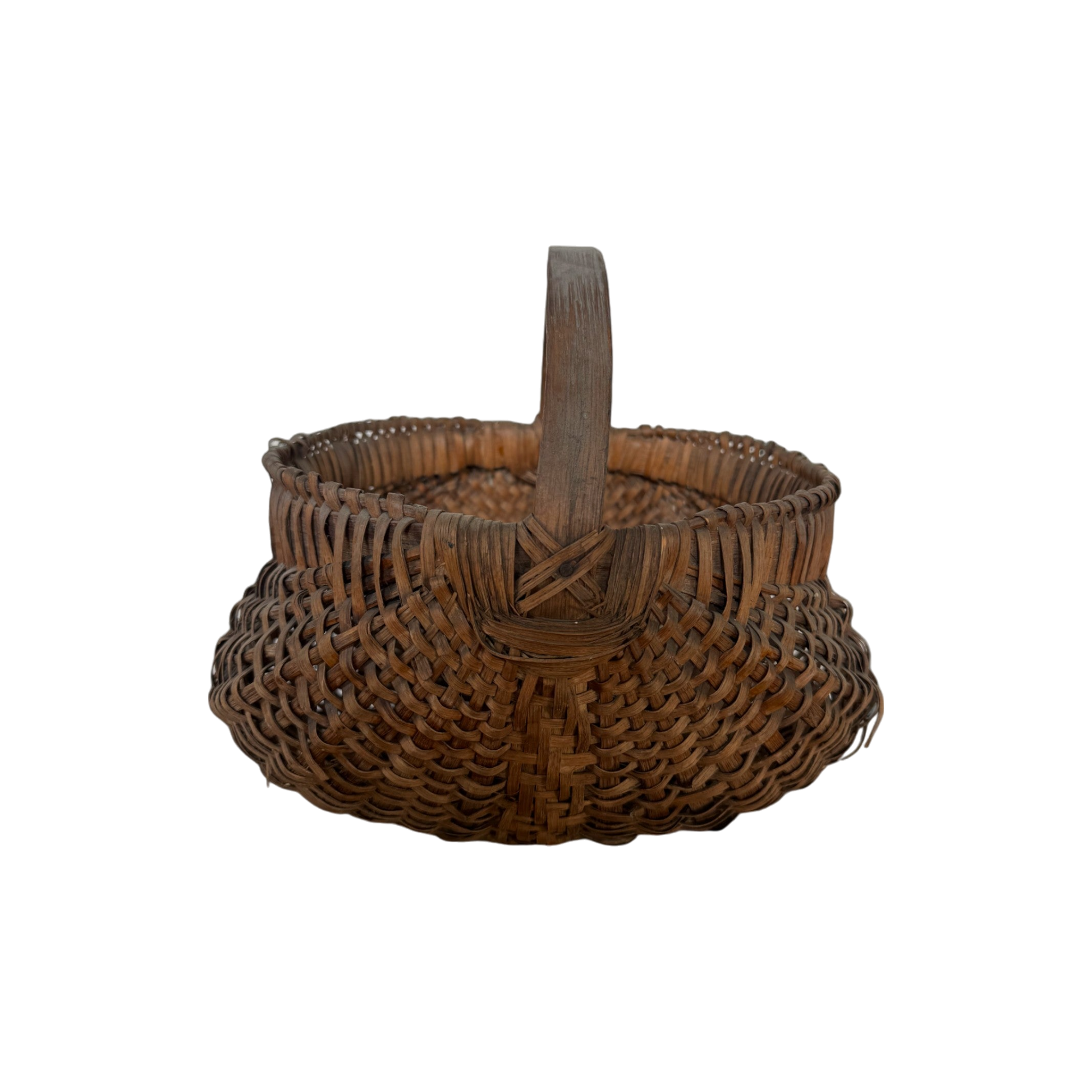 The Antique Gather Basket II by Shoppe Maison features a sturdy handle, rounded bottom, and decorative pattern. Reminiscent of antique buttocks baskets, this woven wicker basket appears empty and is displayed against a black background. The detailed and intricate weaving technique gives it a rustic, handcrafted feel perfect for decorative purposes.