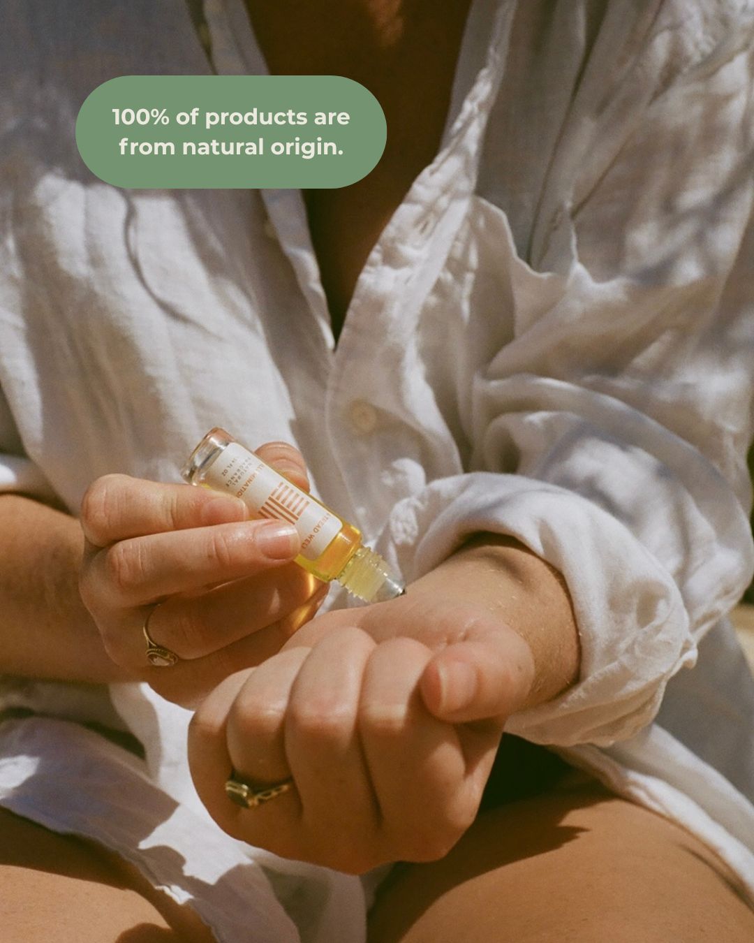 A person in a white shirt applies & Tread Well's Natural Fragrance – Illumination roll-on to their wrist. A text bubble reads, "100% of products are from natural origin for stress relief.