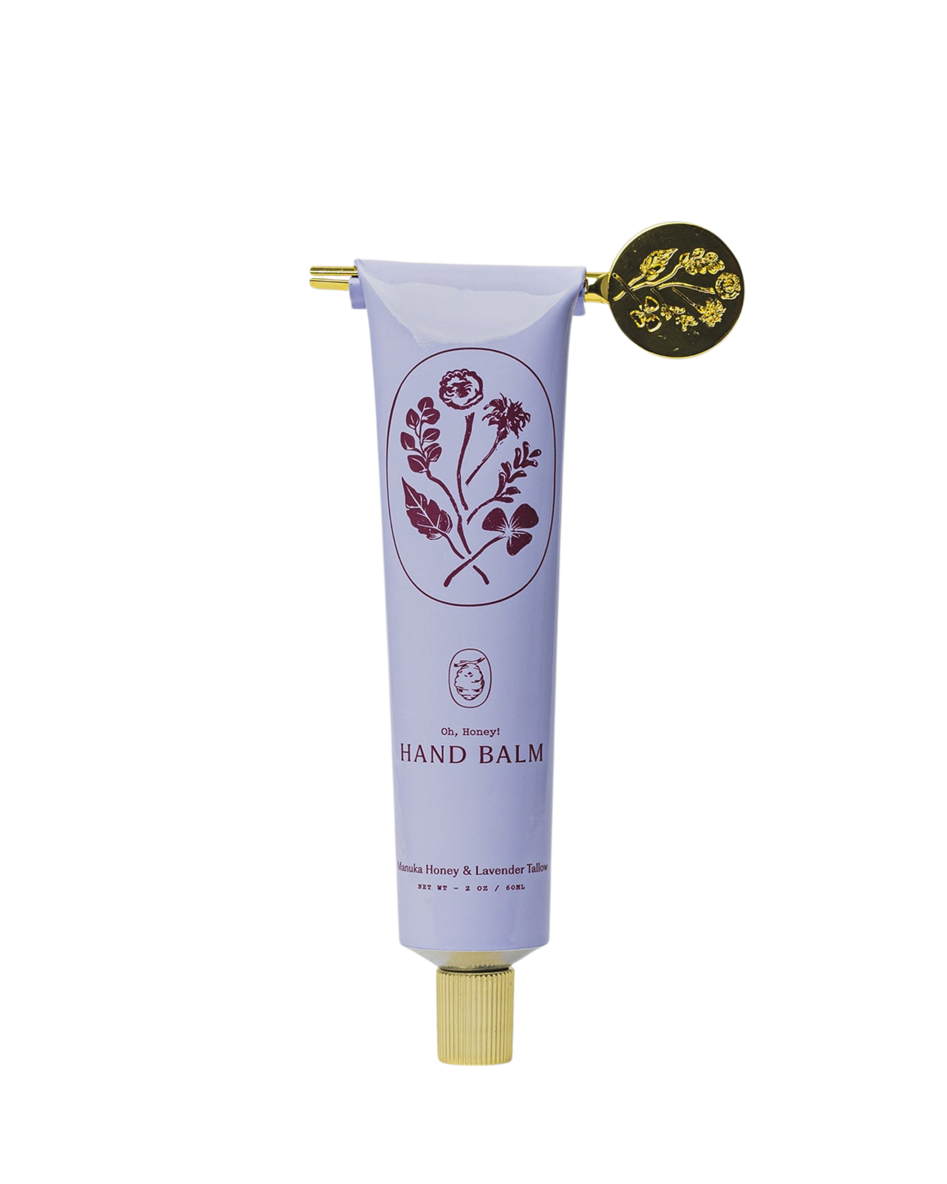 A lavender tube of My Neighbor’s Tallow Manuka Honey & Lavender hand balm with a gold cap and key, decorated with floral graphics and the text "Hand Balm, Danish Manuka Honey & Lavender Tales.