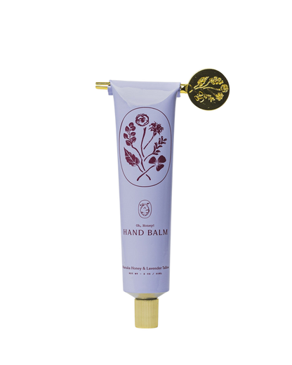 A lavender tube of My Neighbor’s Tallow Manuka Honey & Lavender hand balm with a gold cap and key, decorated with floral graphics and the text "Hand Balm, Danish Manuka Honey & Lavender Tales.