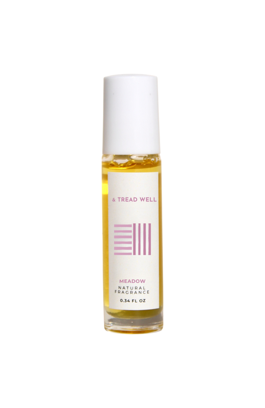 A small glass bottle of & Tread Well Natural Fragrance – Meadow, an organic floral perfume with a white cap and pink-and-black label, containing yellow liquid. This Hudson Valley roll-on is handcrafted, elegant, and natural.