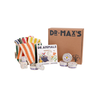 The Dr Maxs New Parent Gift Box features a striped cloth, Dr Animals book, and natural ointment tins like Baby Balm, all with simple, colorful packaging and playful illustrations displayed in front.
